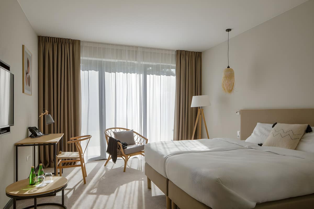 Ein Hotelzimmer mit einem Bett, zwei Stühlen, einem Schreibtisch, einer Lampe und einem Fernseher.