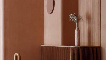 A modern, cozy room with a plush brown sofa, a small round table, and a decorative vase on a wall.
