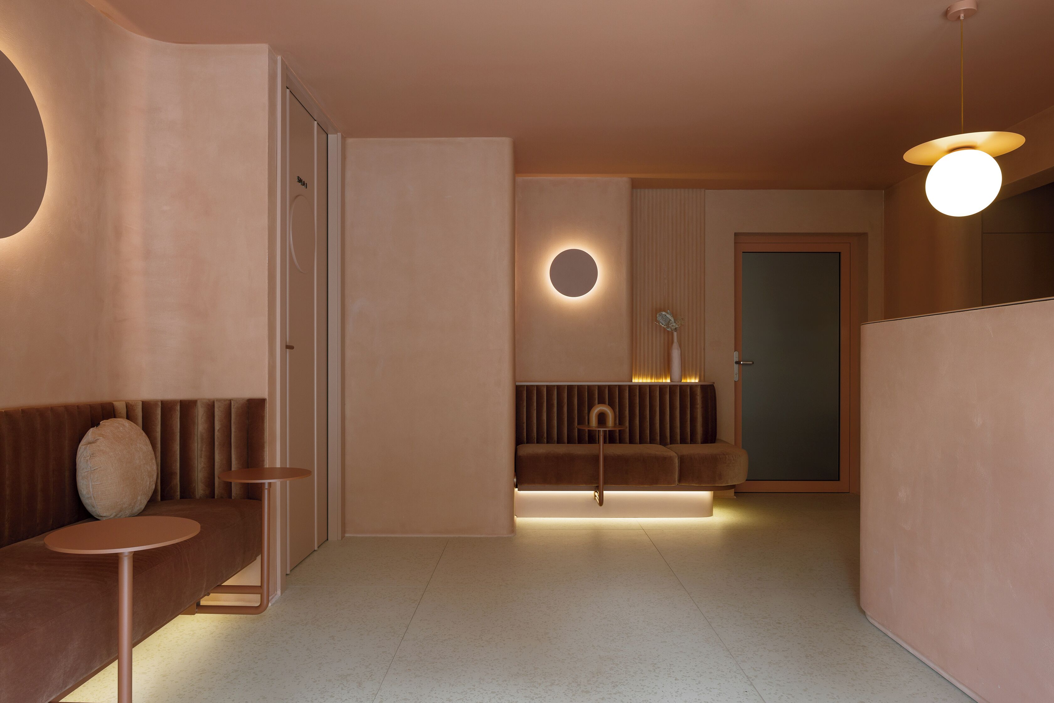 A modern interior with a seating area, a round illuminated wall feature, and a door.