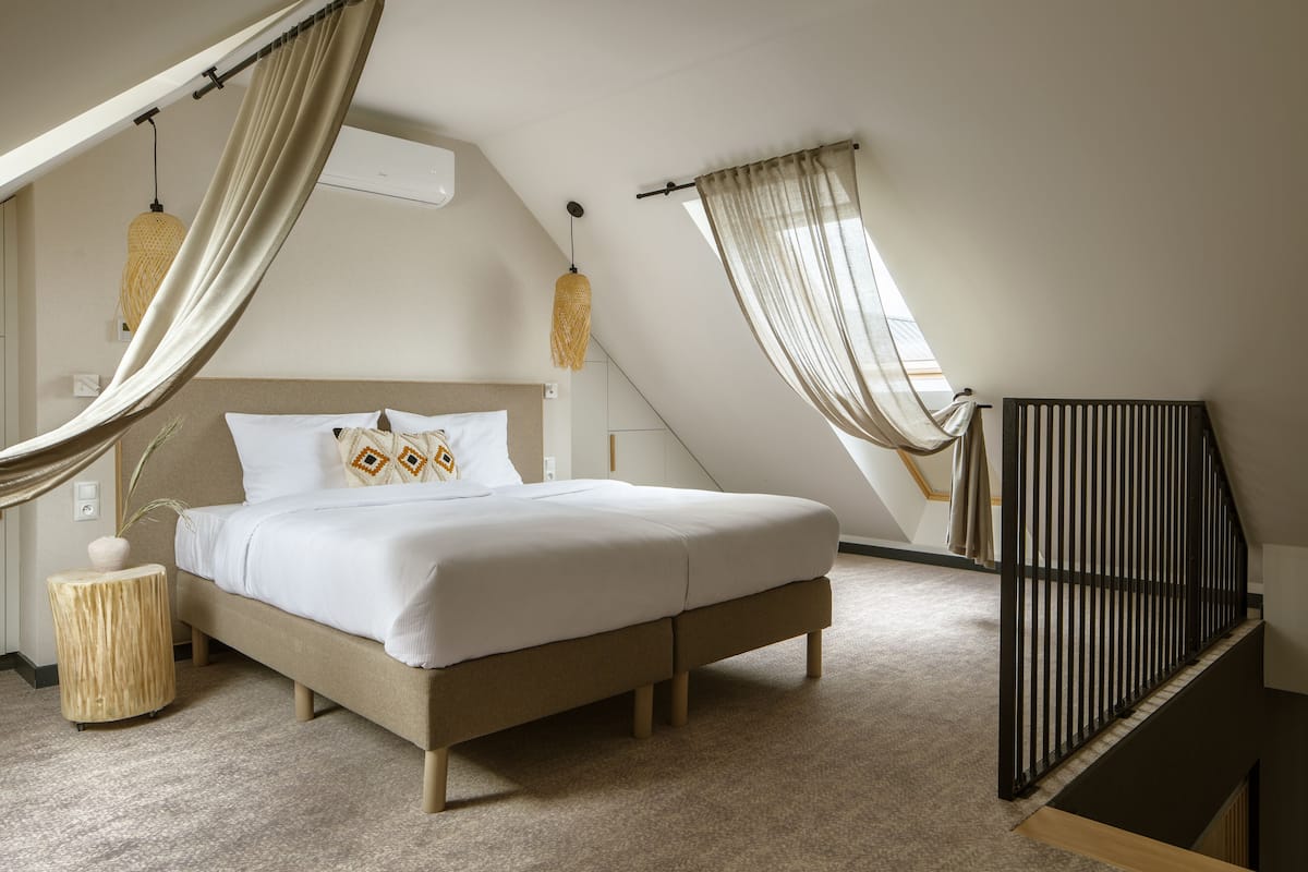 Ein Schlafzimmer mit Bett, Nachttisch, Hängelampe und einem Fenster mit Vorhängen.