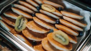 A tray of pancakes with sliced kiwi and blueberries.