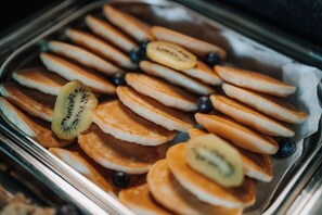 A tray of pancakes with sliced kiwi and blueberries.