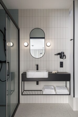 A modern bathroom with a white sink, a large mirror, and a hairdryer on the wall. - Saltic Resort & SPA ŁEBA (Leba)
