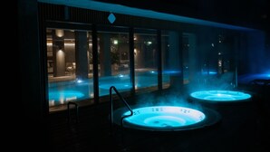 A spa area with two hot tubs and a glass-enclosed pool.