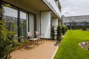 A modern building with large windows, a wooden deck, and a well-maintained lawn. - Saltic Resort & SPA ŁEBA (Leba)