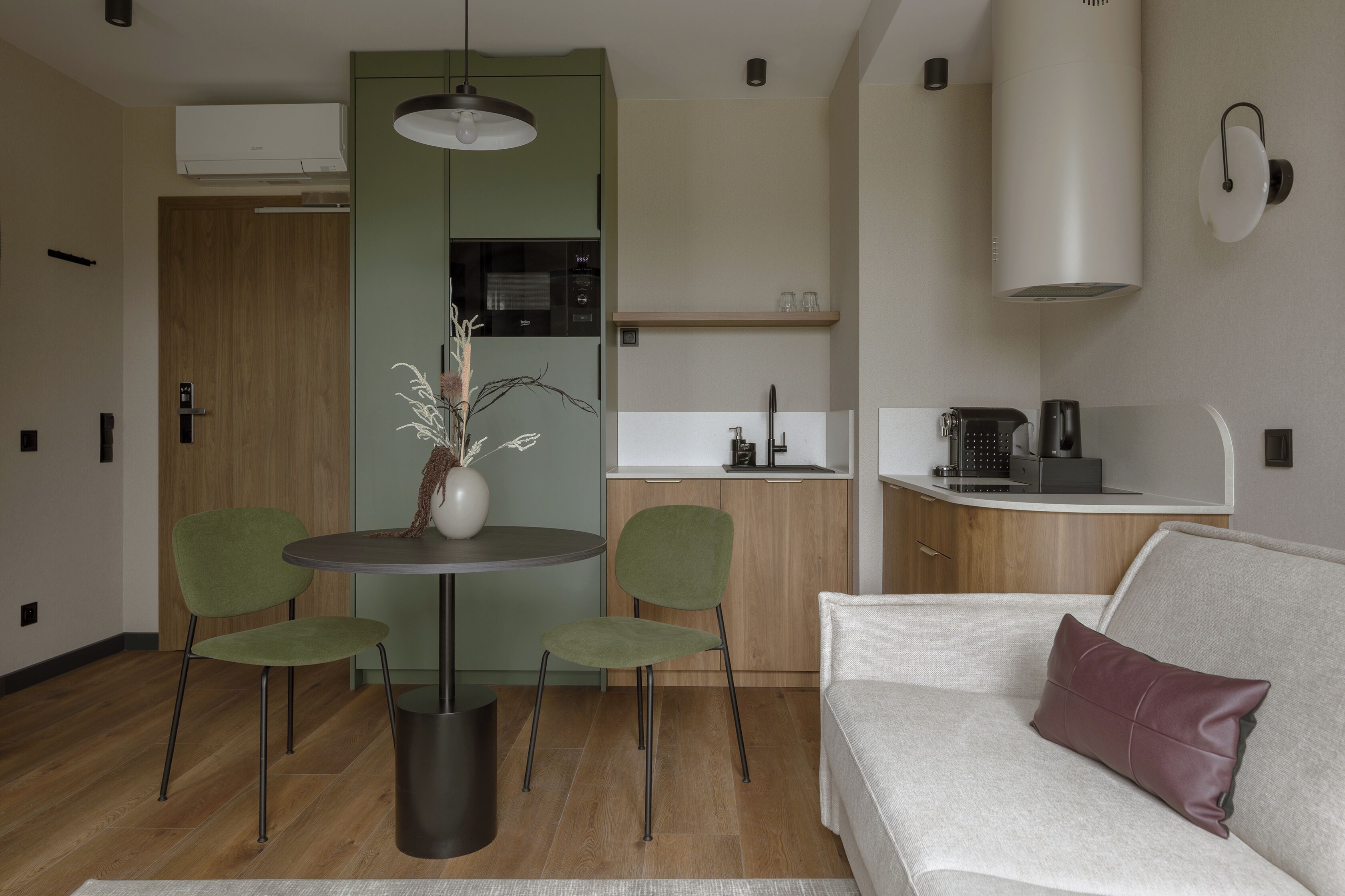 A modern kitchen with a dining area, a sofa, and a coffee machine.
