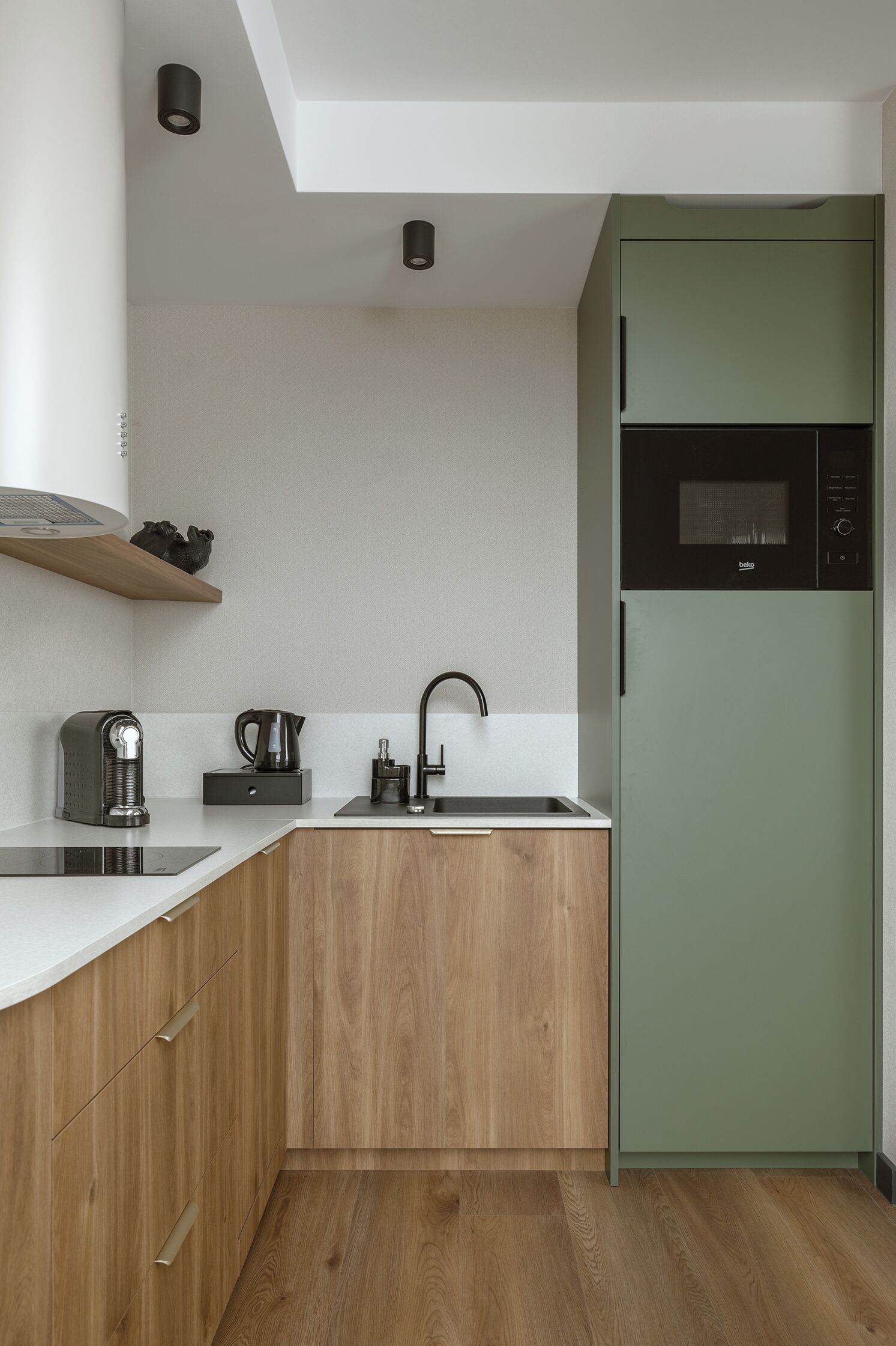 Una cocina moderna con encimera de madera, microondas integrado y refrigerador verde.