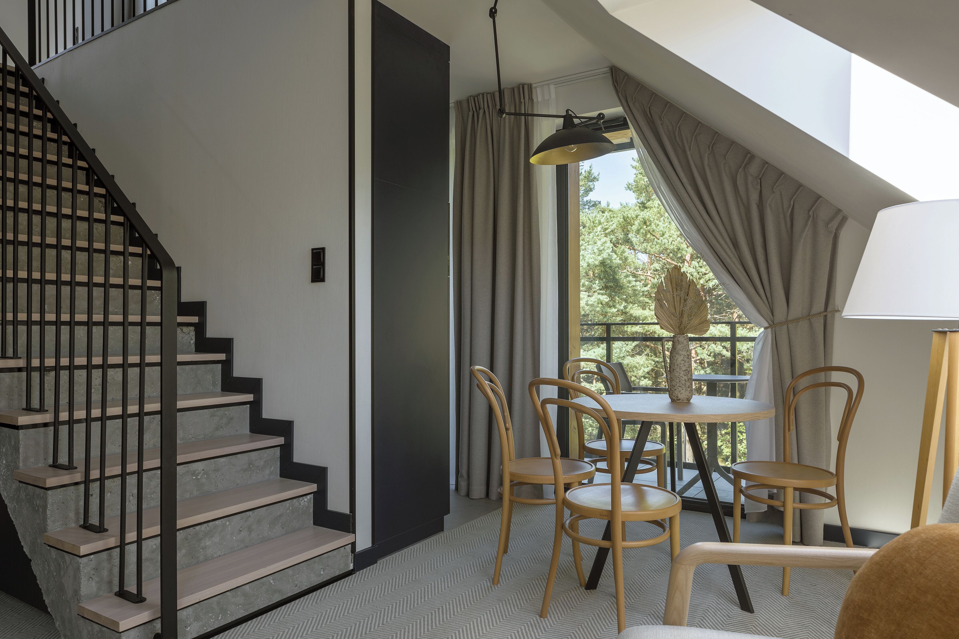 Un interior moderno con una escalera, comedor y ventanas amplias.