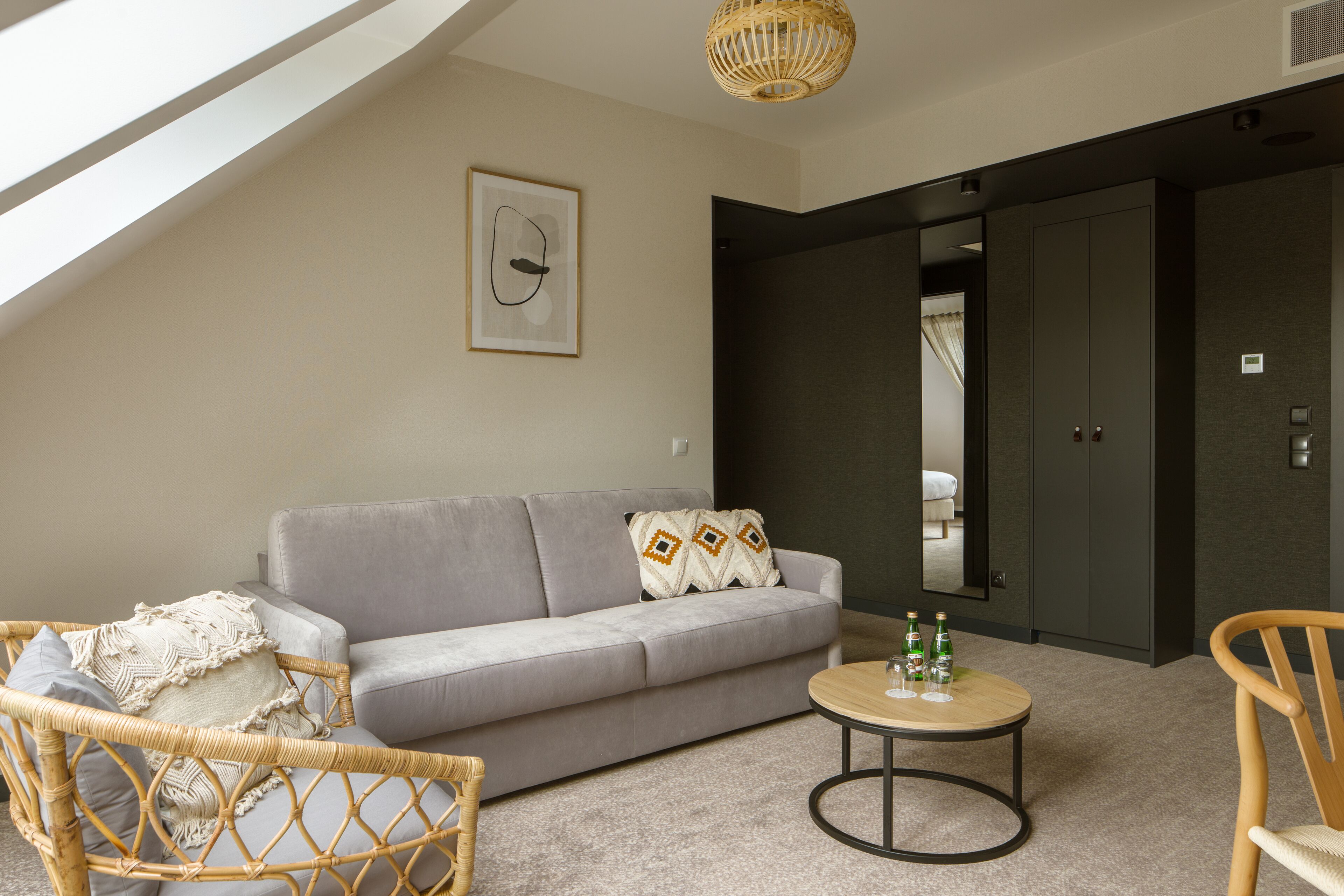 A modern living room with a grey sofa, wicker chair, and a round coffee table.