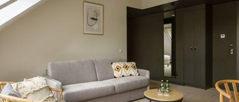 A modern living room with a grey sofa, wicker chair, and a round coffee table.