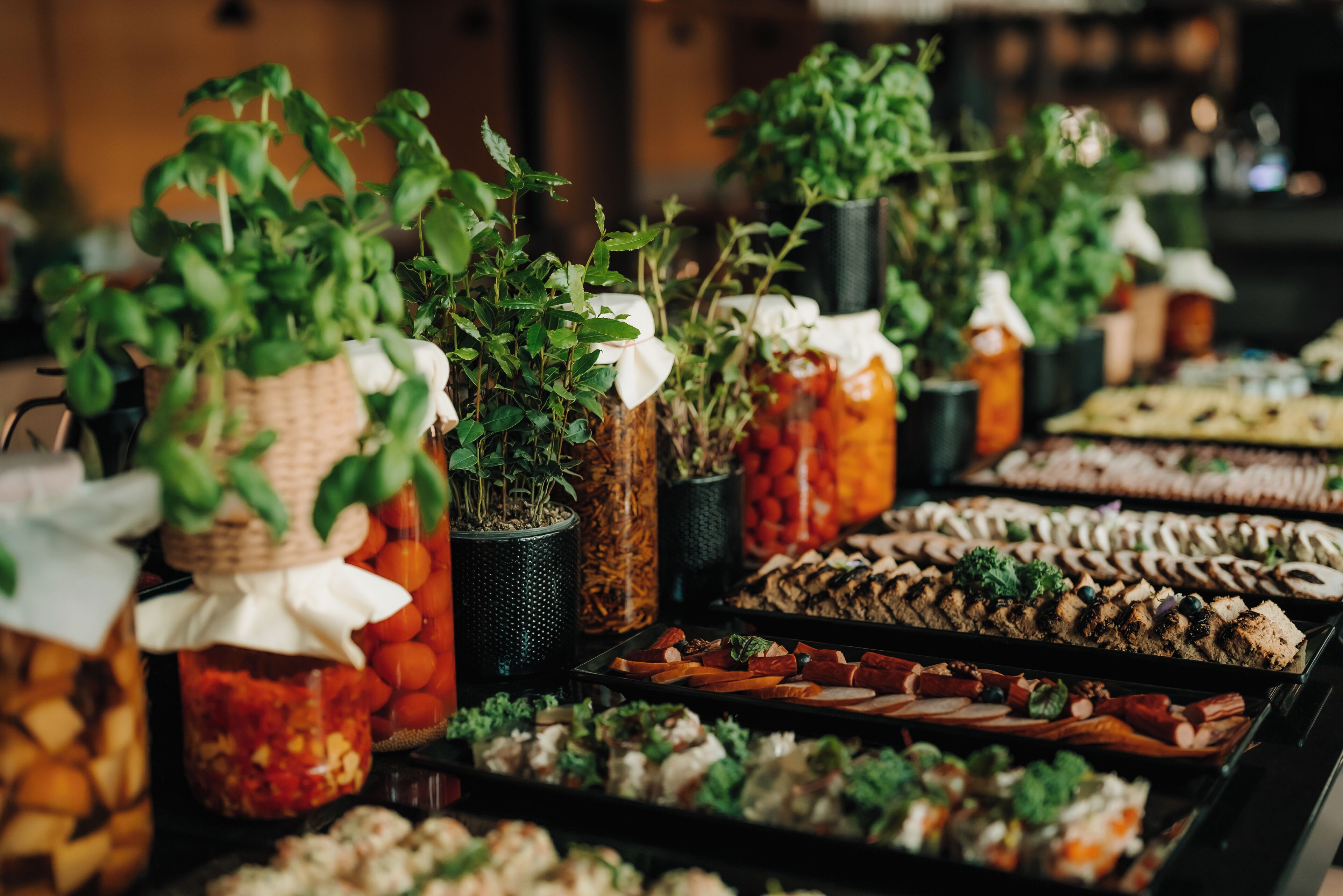 A buffet with various food items and potted plants.