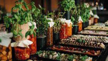 A buffet with various food items and potted plants.