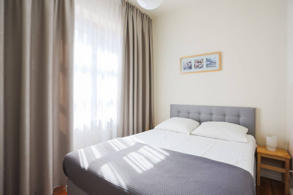 A neatly arranged hotel room with a large bed, a bedside table with a lamp, and a framed picture on the wall.