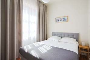 A neatly arranged hotel room with a large bed, a bedside table with a lamp, and a framed picture on the wall.