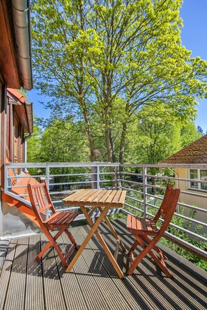 Une terrasse en bois avec deux chaises et une table en bois, donnant sur une étendue d’eau et des arbres.