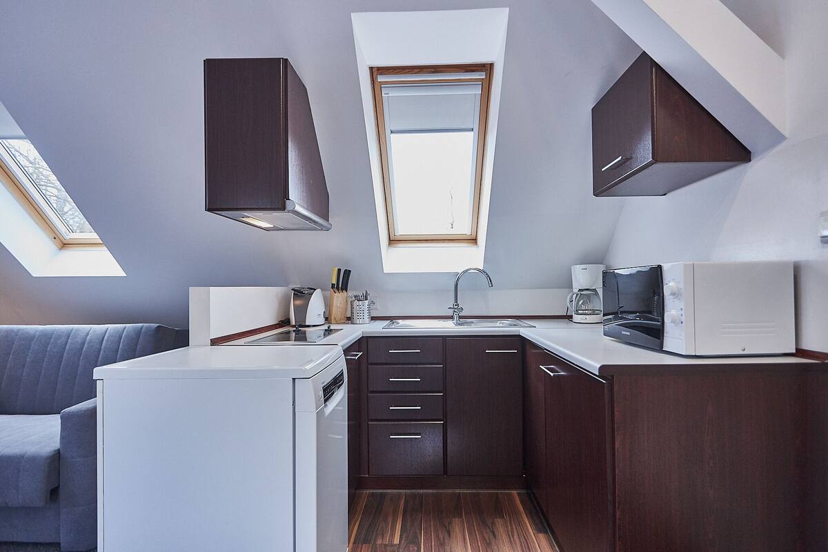 A compact kitchen with a skylight, a built-in microwave, and a coffee maker.