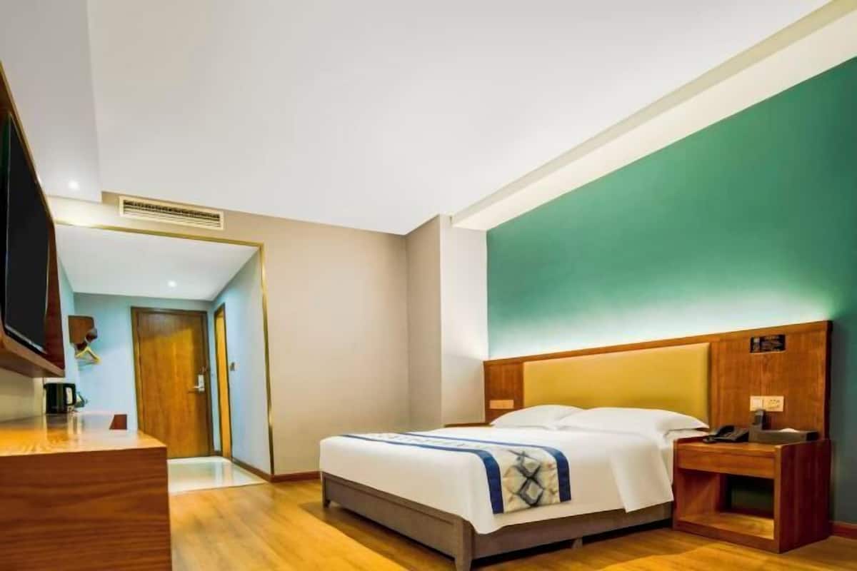 A hotel room with a bed, bedside table, and a television.