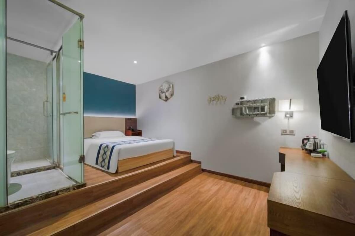Een hotelkamer met een bed, bureau, televisie en douche.
