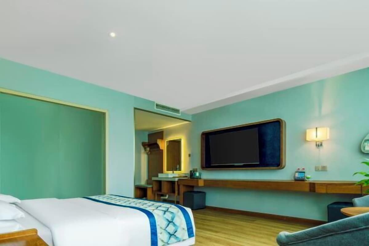 Een hotelkamer met een bed, een bureau, een televisie en een spiegel.