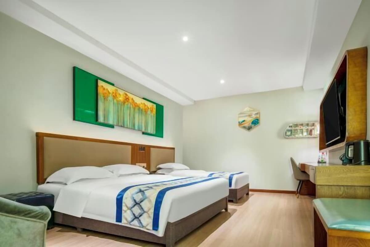 Een hotelkamer met een groot bed, een bureau met stoel, een televisie en kunstwerken aan de muur.
