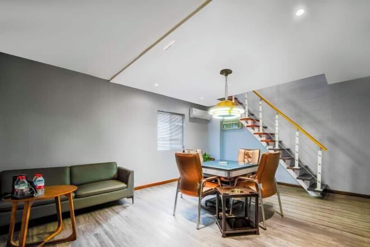 A modern living room with a sofa, dining table, chairs, and a staircase.