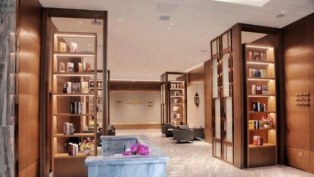A modern lobby with marble flooring, wooden bookshelves, comfortable seating, and a reception desk. - HengYangYi’nian Yuexiang Hotel (Hengyang)