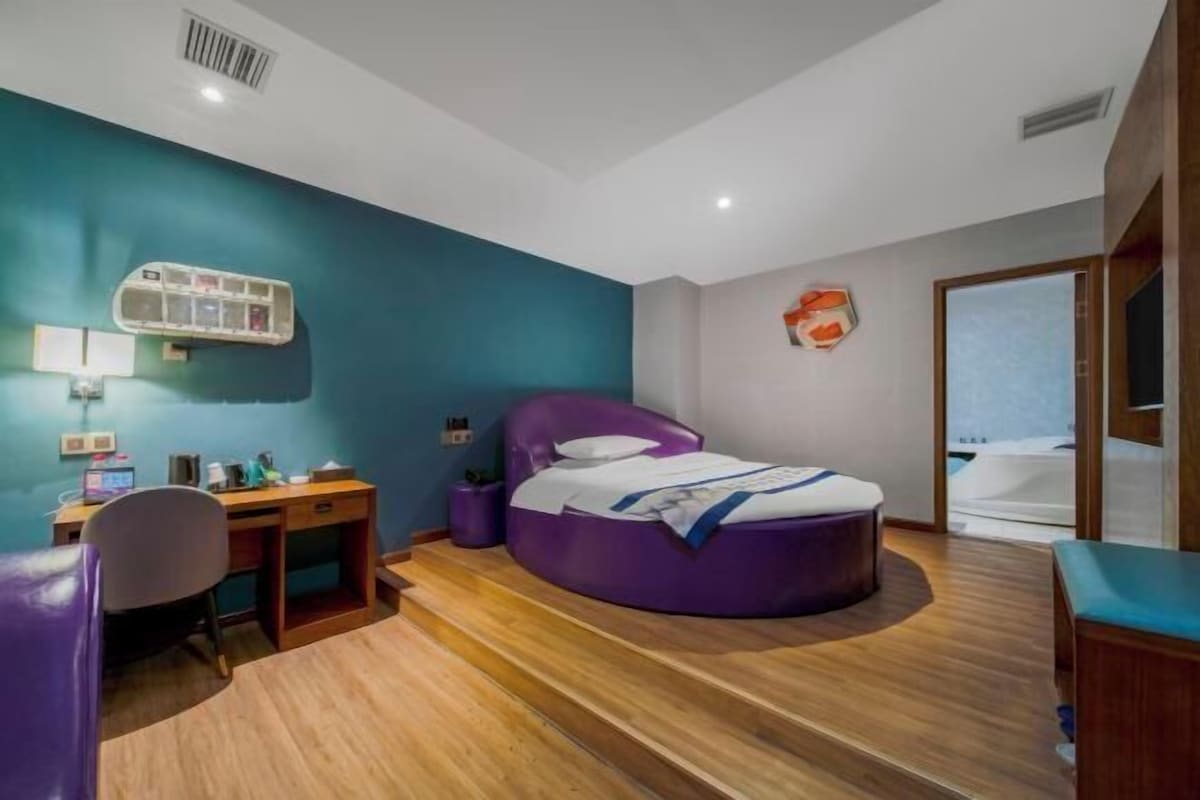 Een moderne slaapkamer met een gebogen bed, een bureau en een stoel.