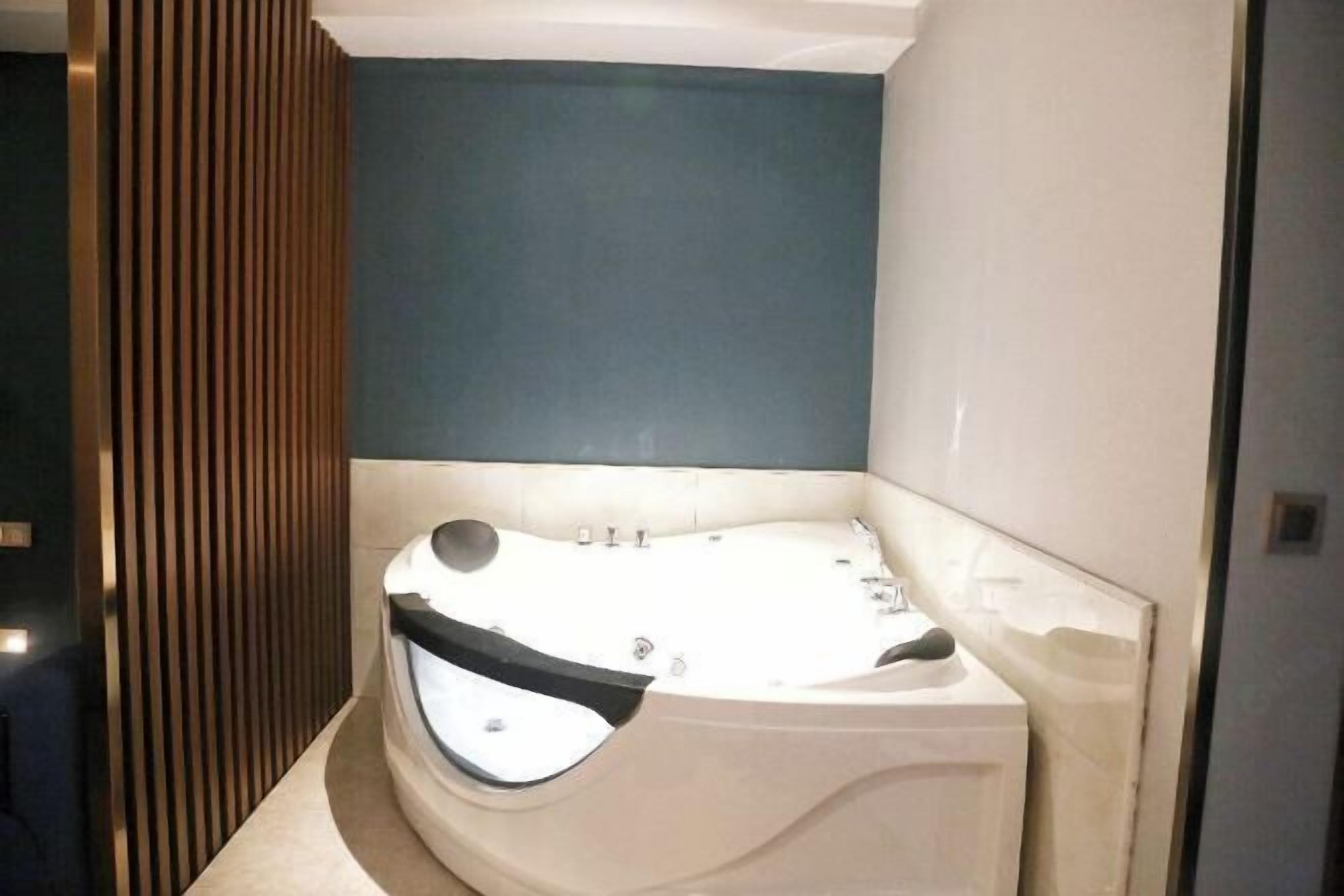 Ein modernes Badezimmer mit einer freistehenden Badewanne, einer Wandverkleidung aus Holz und einer blauen Akzentwand.
