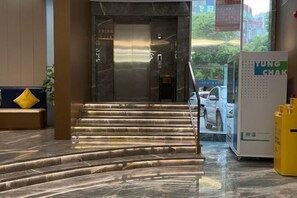 A hotel lobby with a marble staircase leading to an elevator, a reception desk, and a large advertisement. - HengYangYi’nian Yuexiang Hotel (Hengyang)
