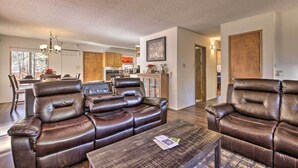 A modern living room with leather sofas, a wooden coffee table, and a dining area in the background. - Hot Tub Hideaway in Pinetop: Bring Your Pet! (Pinetop-Lakeside)