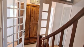 A wooden staircase leading to a room with a wooden door and a chandelier. - Large family house sleeping 16 in the mountains (Font-Romeu-Odeillo-Via)