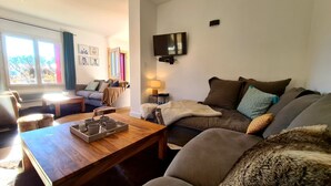 A cozy living room with a sofa, a coffee table, and a TV mounted on the wall. - Large family house sleeping 16 in the mountains (Font-Romeu-Odeillo-Via)