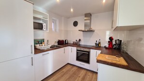 A modern kitchen with white cabinets, a built-in oven, a microwave, and a coffee maker. - Large family house sleeping 16 in the mountains (Font-Romeu-Odeillo-Via)