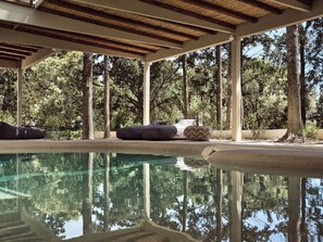 A pool area with a clear reflection of trees, wooden deck, and seating. - Periyali Villas (Zakynthos)