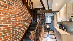 A spiral staircase with a brick wall on one side and a wooden staircase railing. - Holiday home in Melreux-Hotton with sauna (Melreux-Hotton)