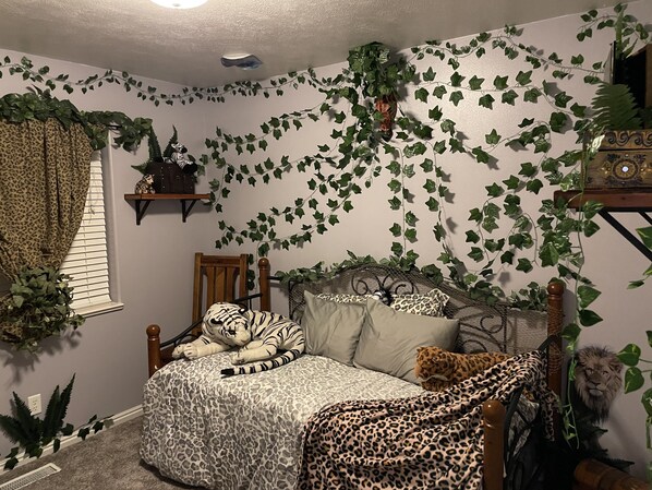 A bedroom with a bed, a chair, and a leopard-print bedspread.