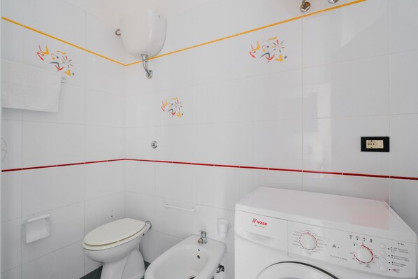 Un baño con inodoro, bidé y lavadora.
