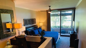 Ein Hotelzimmer mit Bett, Schreibtisch, Stuhl, Lampe und Blick ins Freie.