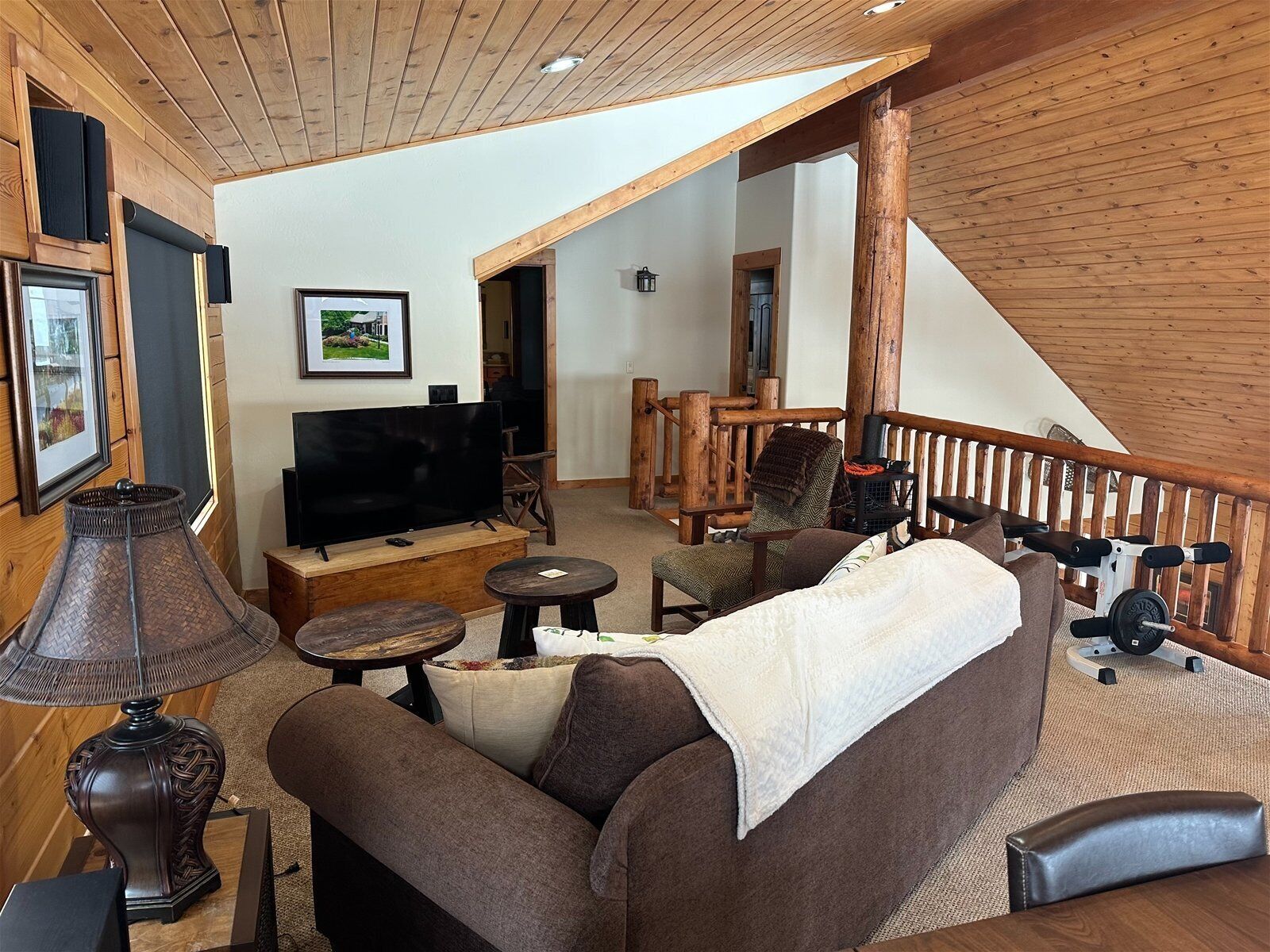 Ein gemütliches Wohnzimmer mit einer Couch, einem Fernseher und einer Holztreppe.