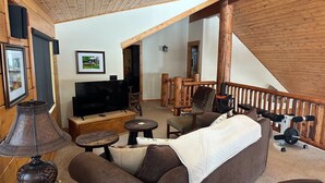A cozy living room with a sofa, TV, and a wooden staircase. - Larkspur Luxury - Crested Butte (Crested Butte)