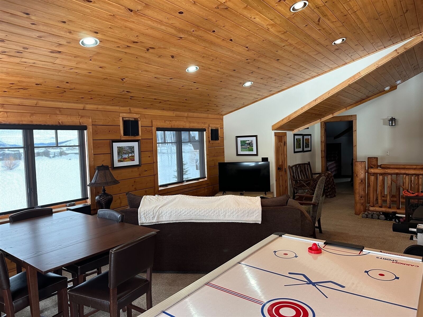 Une pièce confortable avec un plafond en bois, une télévision, une table et un canapé.
