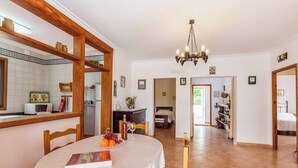 A dining area with a round table, chairs, a chandelier, and a view into a bedroom. - Private pool and 1.7km to Mallorca’s Beaches! (Palma de Mallorca)
