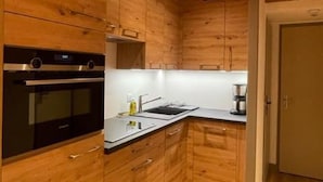 Une cuisine compacte dotée de meubles en bois, d’un four encastré, d’un évier et d’une machine à café.