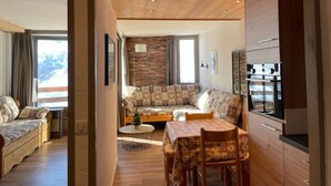 Un salon confortable avec un canapé, une table à manger et des chaises, ainsi qu’un coin cuisine équipé d’un réfrigérateur.