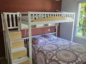 A bunk bed with a wooden ladder, a patterned bedspread, and a window with a view of greenery. - Central Apartment in Biscarrosse with Pool and Terrace, Beach Nearby, Sleeps 4 (Biscarrosse)