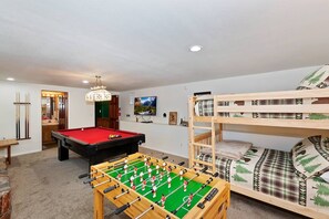 Ein Zimmer mit Kicker, Billardtisch und Etagenbett.