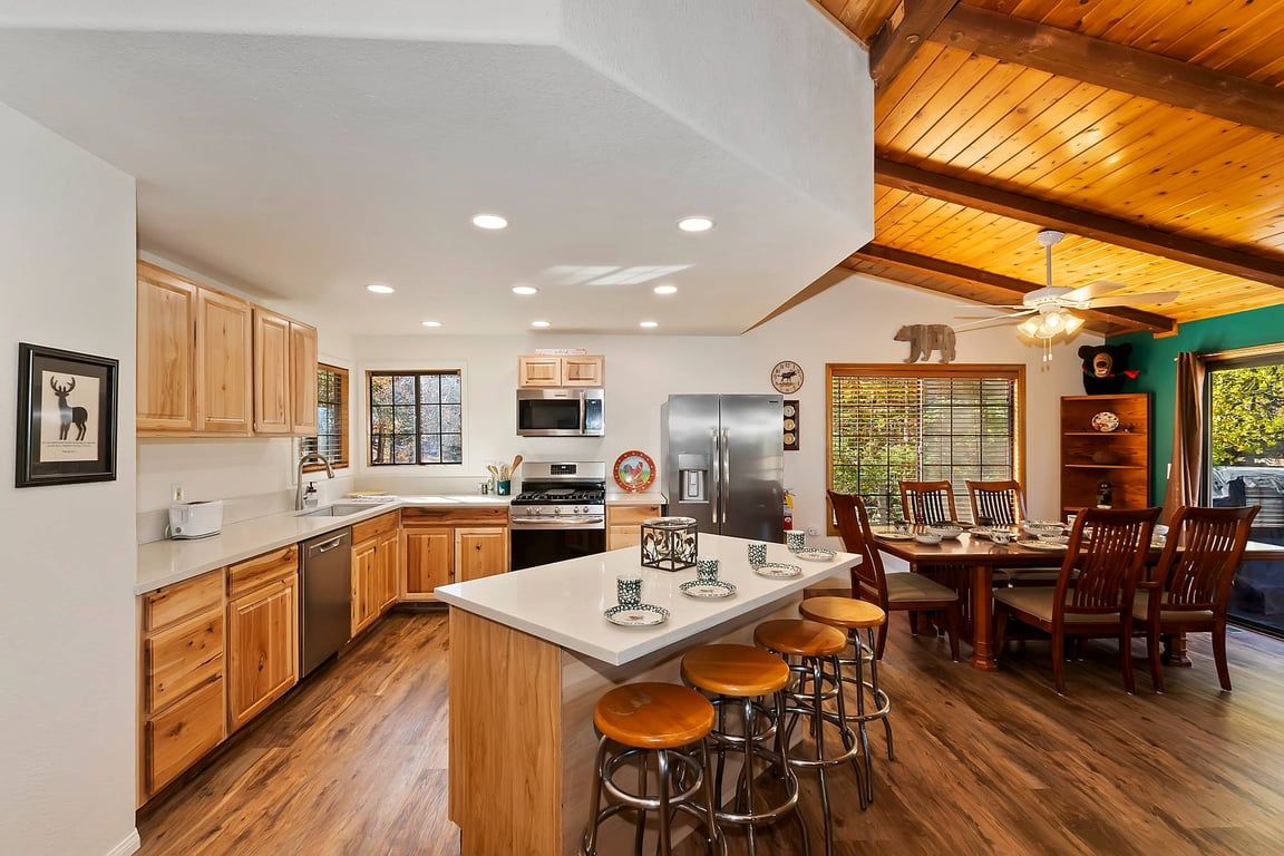 Una cocina amplia con armarios de madera, una isla central con taburetes y un comedor con sillas.