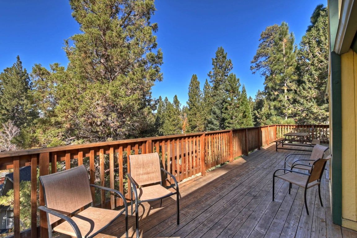 Une terrasse en bois avec des sièges d’extérieur et une vue sur de grands arbres.