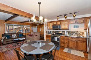 Un espacio habitable compacto con kitchenette, comedor y zona de estar con sofá y sillas.