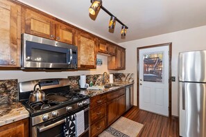A kitchen with wooden cabinets, stainless steel appliances, a granite countertop, and a door leading to a balcony.